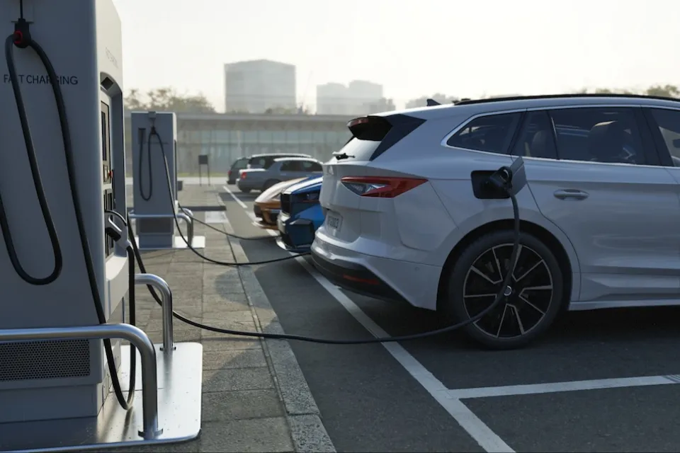 Row of vehicles parked and plugged in at EV charging station.